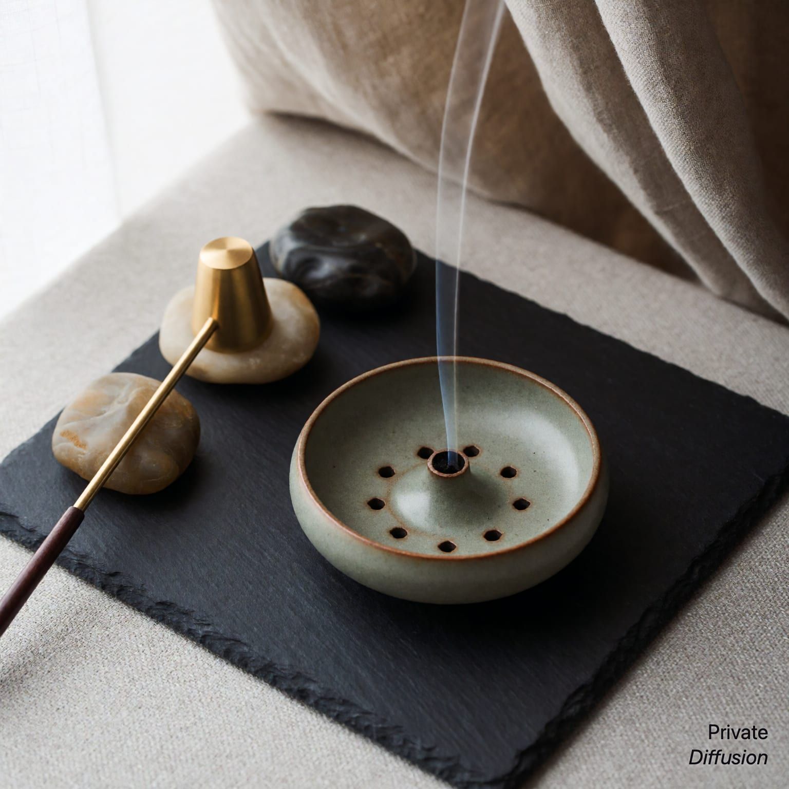 A ceramic incense holder emits a thin smoke trail on a slate tabletop.