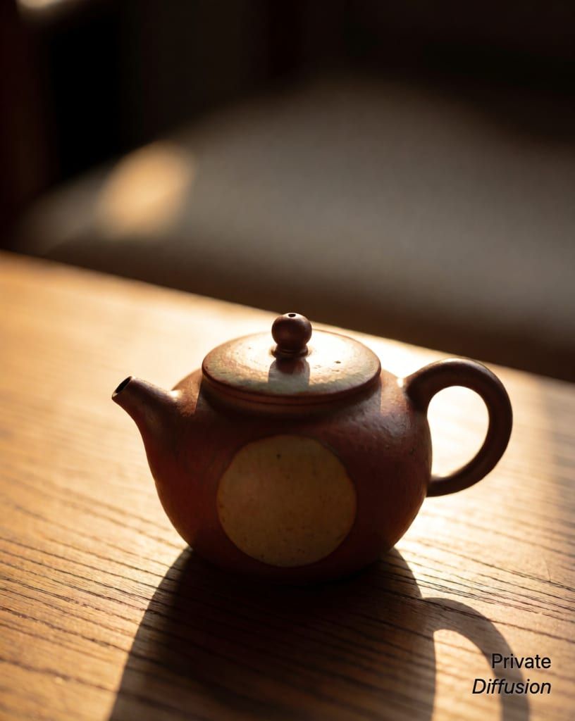 a ceramic teapot on a wooden table, with golden hour added